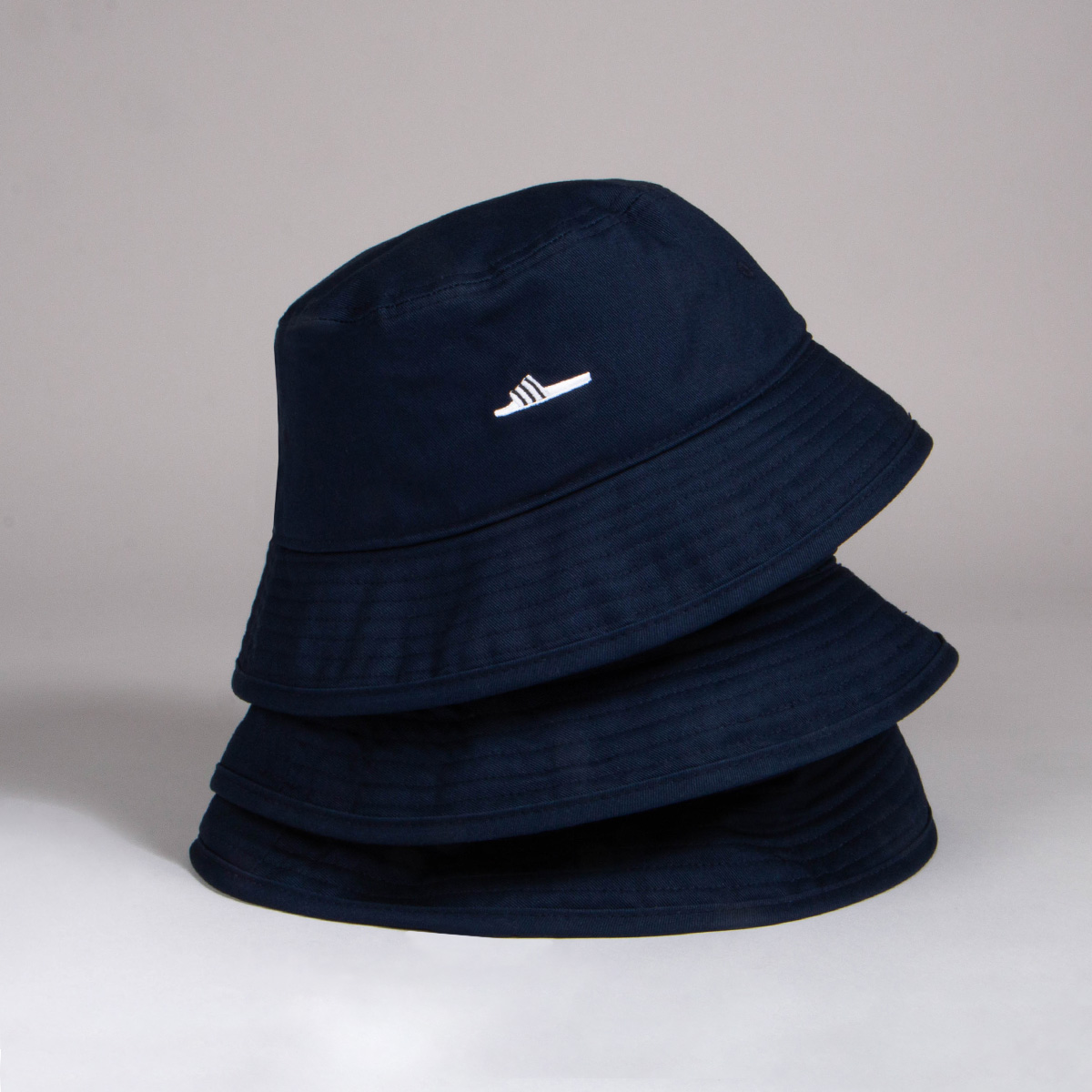 Three black Adidas bucket hats stacked on top of each other.